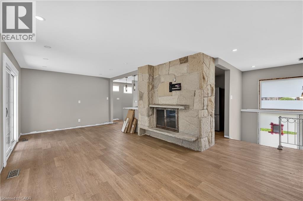 Open-concept living space featuring wood-finish flooring, recessed lighting, and a prominent stone fireplace - 515 Bobbybrook Drive, London, ON - Indoor With Fireplace