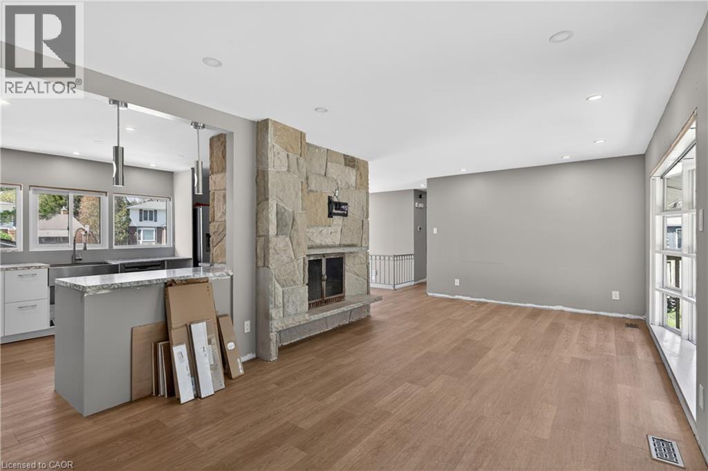 Open-concept living space featuring wood-finish flooring, a stone-clad fireplace, and recessed lighting - 515 Bobbybrook Drive, London, ON - Indoor With Fireplace