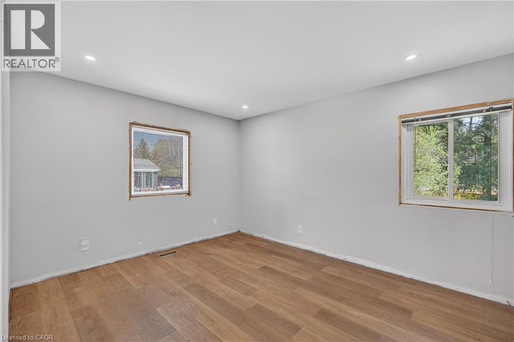 Bright room featuring wood-finish flooring, light grey walls, two windows providing natural illumination, and recessed ceiling lights - 515 Bobbybrook Drive, London, ON - Indoor Photo Showing Other Room