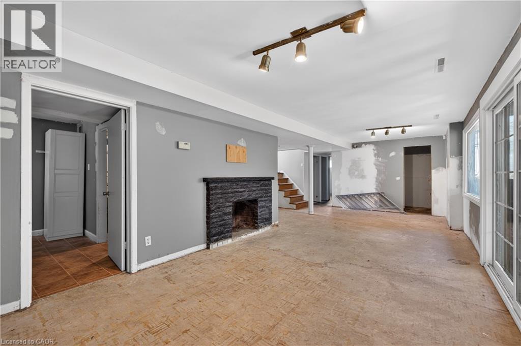 Spacious lower level featuring a dark stone fireplace, track lighting, and double-paned glass sliding doors - 515 Bobbybrook Drive, London, ON - Indoor With Fireplace