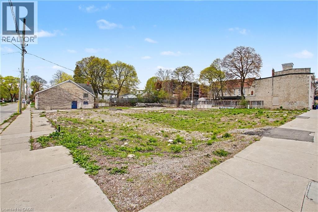 Expansive land parcel featuring existing paved sidewalks and mature trees in the background - 868 King Street E, Cambridge, ON