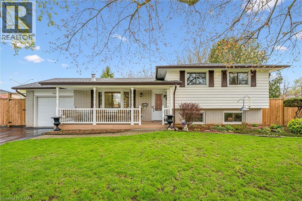 Split-level residence featuring brick and siding exterior, a front porch with white railing, and an attached garage - 574 Sprucehill Avenue, Waterloo, ON - Outdoor With Deck Patio Veranda