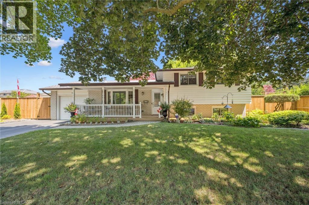 Split-level residence featuring a brick and siding exterior, an attached garage, and a covered porch with white railings - 574 Sprucehill Avenue, Waterloo, ON - Outdoor With Deck Patio Veranda