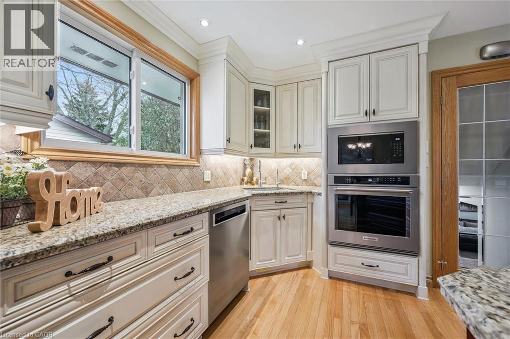 Kitchen featuring light wood-finish flooring, white cabinetry, granite-style countertops, and a tile backsplash - 574 Sprucehill Avenue, Waterloo, ON - Indoor Photo Showing Kitchen With Upgraded Kitchen