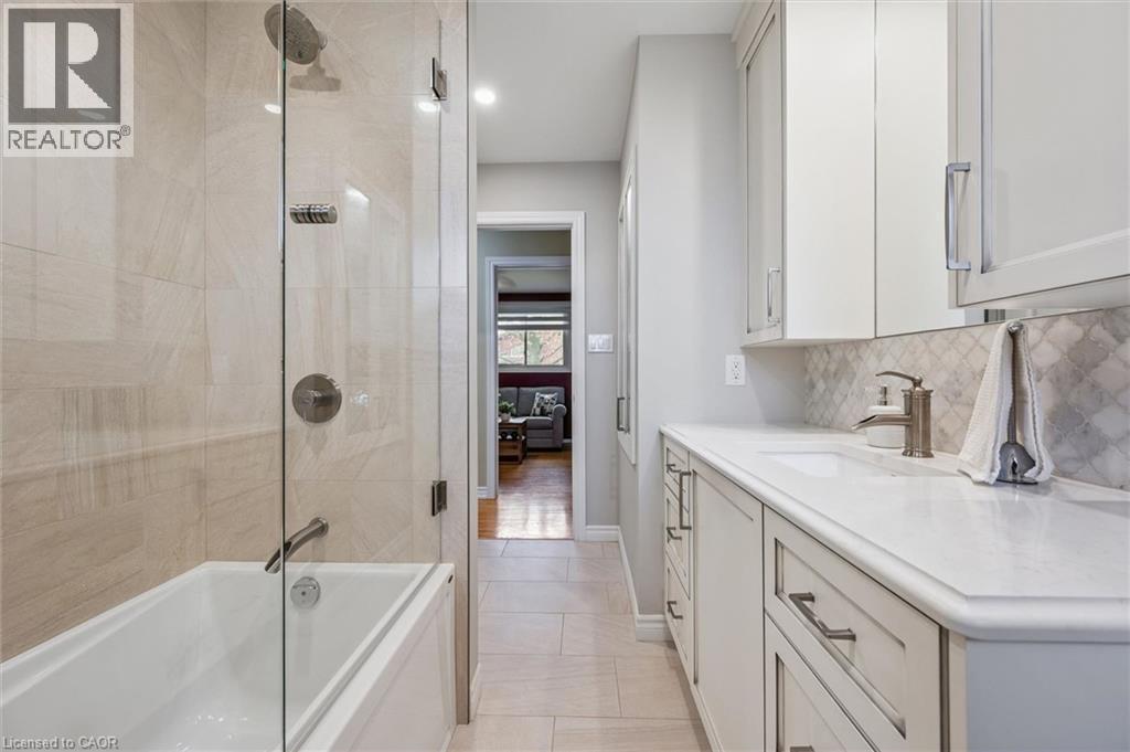 Contemporary bathroom featuring a bathtub with a glass shower enclosure, large format tile surround, and a rain shower head - 574 Sprucehill Avenue, Waterloo, ON - Indoor Photo Showing Bathroom