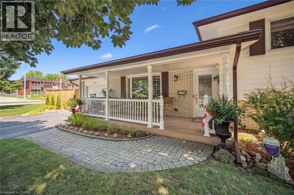 Front exterior featuring a covered porch with white railing, wood-finish decking, and decorative columns - 574 Sprucehill Avenue, Waterloo, ON - Outdoor With Deck Patio Veranda