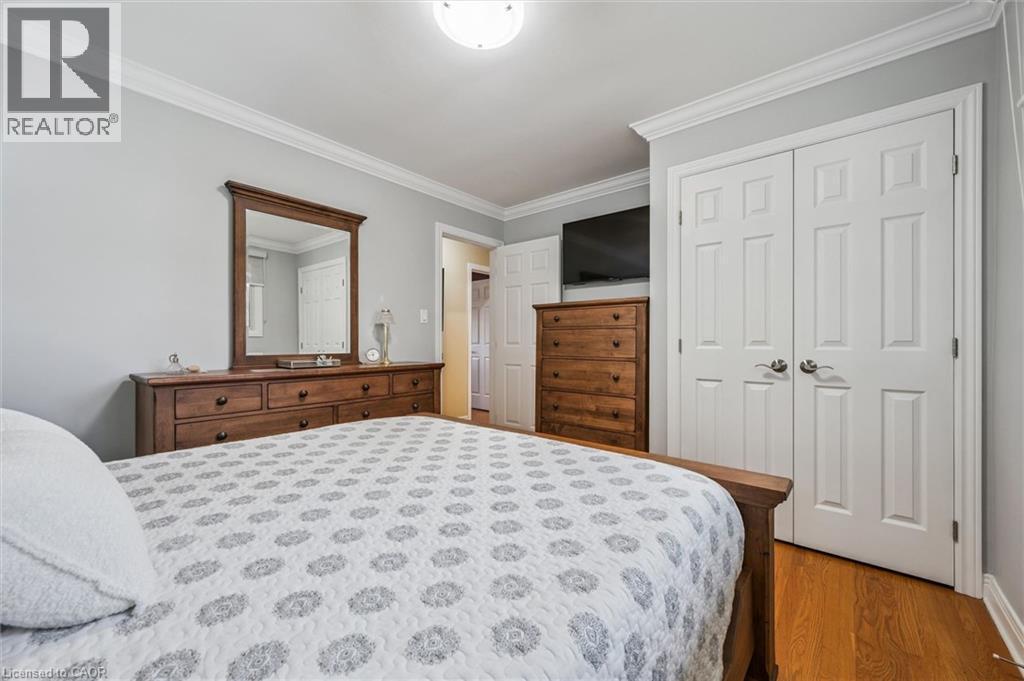 Bedroom featuring light gray walls, white crown molding, wood-finish flooring, and a double-door closet with paneled doors - 574 Sprucehill Avenue, Waterloo, ON - Indoor Photo Showing Bedroom
