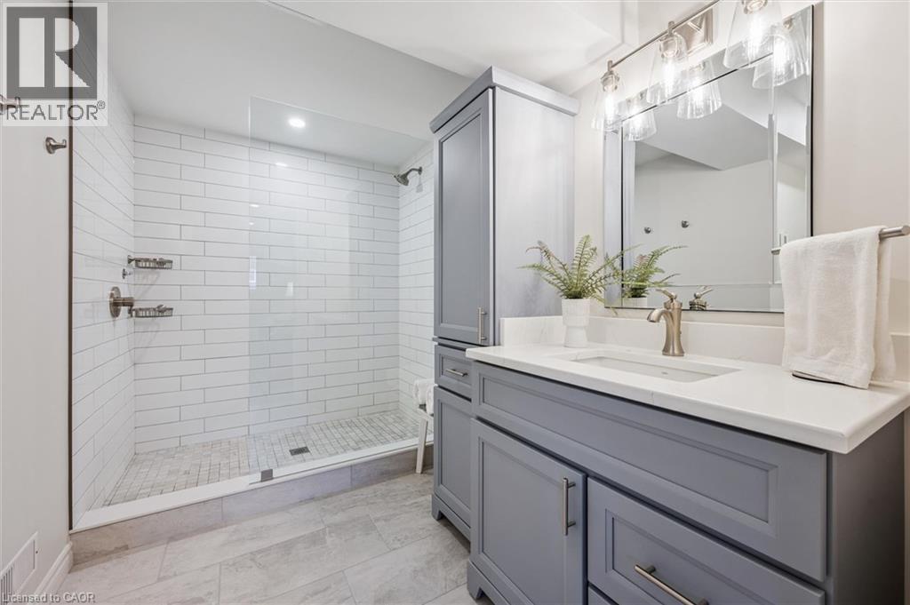 Bathroom featuring a glass-enclosed shower with subway tile, a gray vanity with a quartz countertop, and a brushed nickel faucet - 574 Sprucehill Avenue, Waterloo, ON - Indoor Photo Showing Bathroom