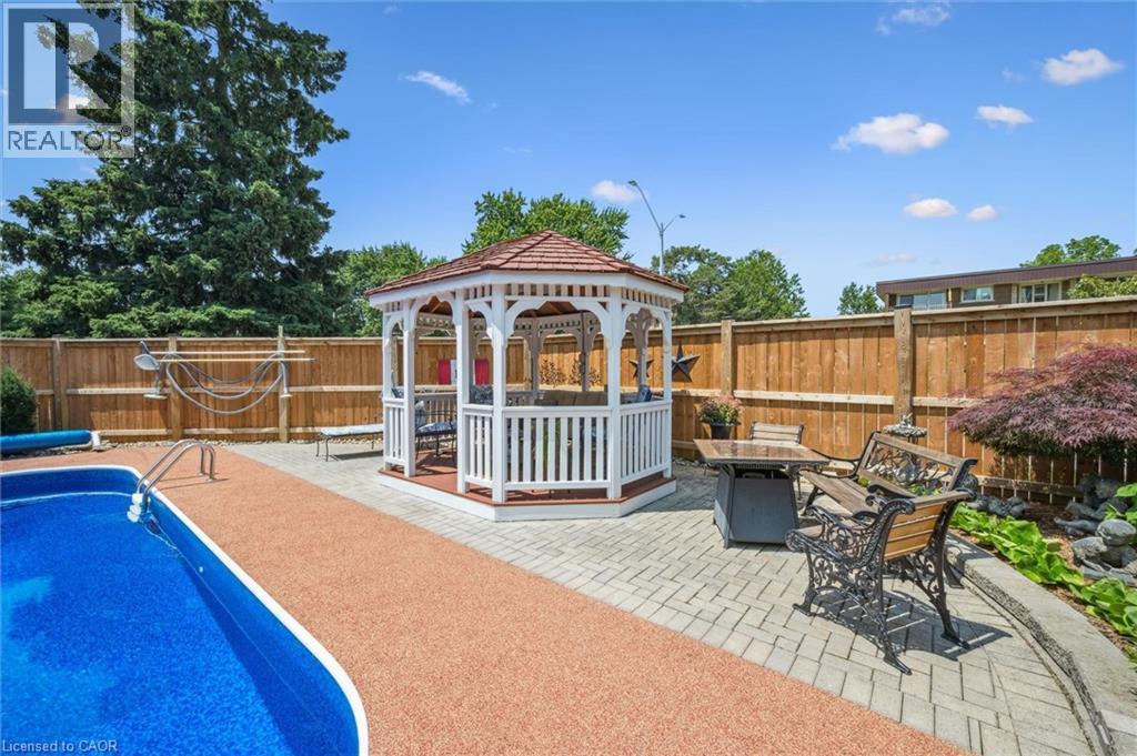 Backyard oasis featuring an in-ground pool, a white gazebo with a red roof, and a paved patio area - 574 Sprucehill Avenue, Waterloo, ON - Outdoor With Deck Patio Veranda With Backyard
