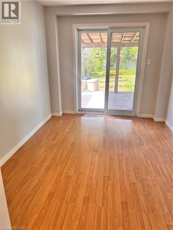 Bright interior space featuring wood-finish flooring and a sliding glass door leading to an outdoor deck - 206 Northmanor Crescent, Kitchener, ON