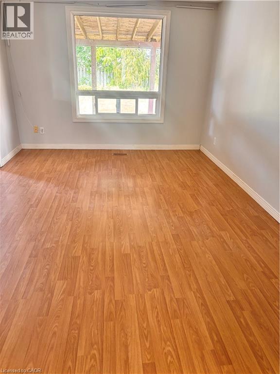 Spacious interior room featuring wood-finish flooring, a large window, and light-toned wall finishes - 206 Northmanor Crescent, Kitchener, ON