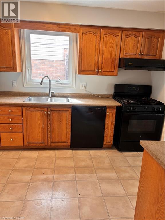 Kitchen featuring wood cabinetry, a double basin stainless steel sink, black range, black dishwasher, and tiled flooring - 206 Northmanor Crescent, Kitchener, ON