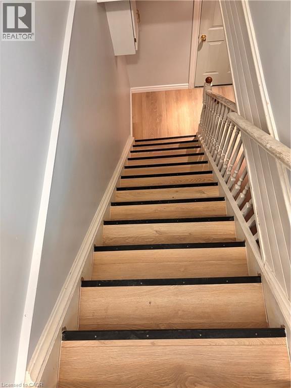 Staircase featuring wood-finish treads with black anti-slip strips, white risers, and a white painted balustrade - 206 Northmanor Crescent, Kitchener, ON