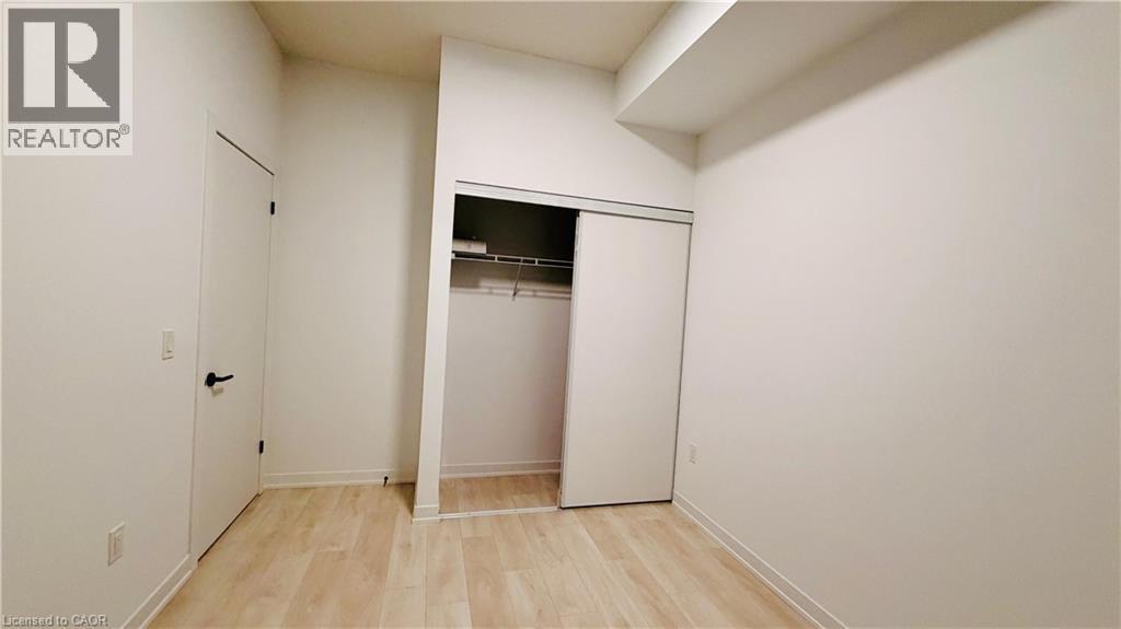 Room featuring light wood-finish flooring, white walls, and a built-in closet with sliding doors - 4878 Powers Common Unit# 301, Burlington, ON - Indoor Photo Showing Other Room