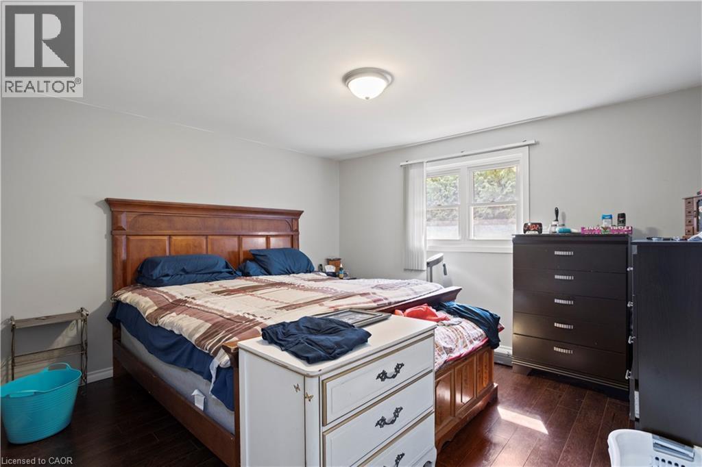 Spacious room featuring dark wood-finish flooring, light gray walls, a window with white trim, and a flush-mount ceiling light fixture - 179 Vancouver Street, London, ON - Indoor Photo Showing Bedroom
