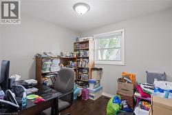 Room featuring wood-finish flooring, a double-hung window with white trim, a flush-mount ceiling light fixture, and light gray painted walls -