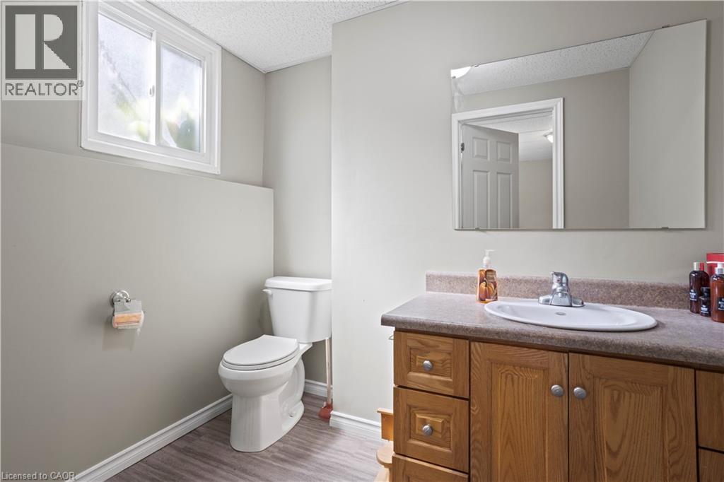 Bathroom featuring a wood-finish vanity with a countertop, an undermount sink, and a large wall-mounted mirror - 179 Vancouver Street, London, ON - Indoor Photo Showing Bathroom