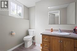 Bathroom featuring a wood-finish vanity with a countertop, an undermount sink, and a large wall-mounted mirror -