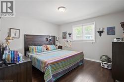 Bedroom featuring wood-finish flooring and a central window with blinds -