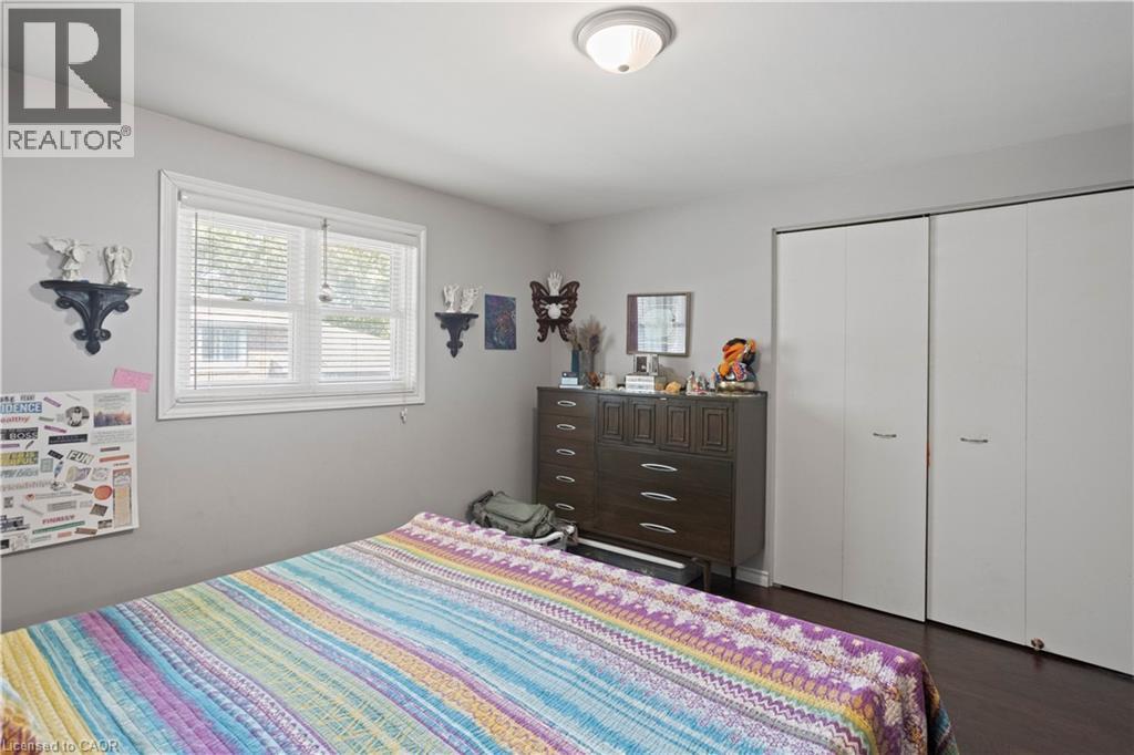 Neutral wall color with a window featuring blinds, dark wood-finish flooring, and bi-fold closet doors - 179 Vancouver Street, London, ON - Indoor Photo Showing Bedroom