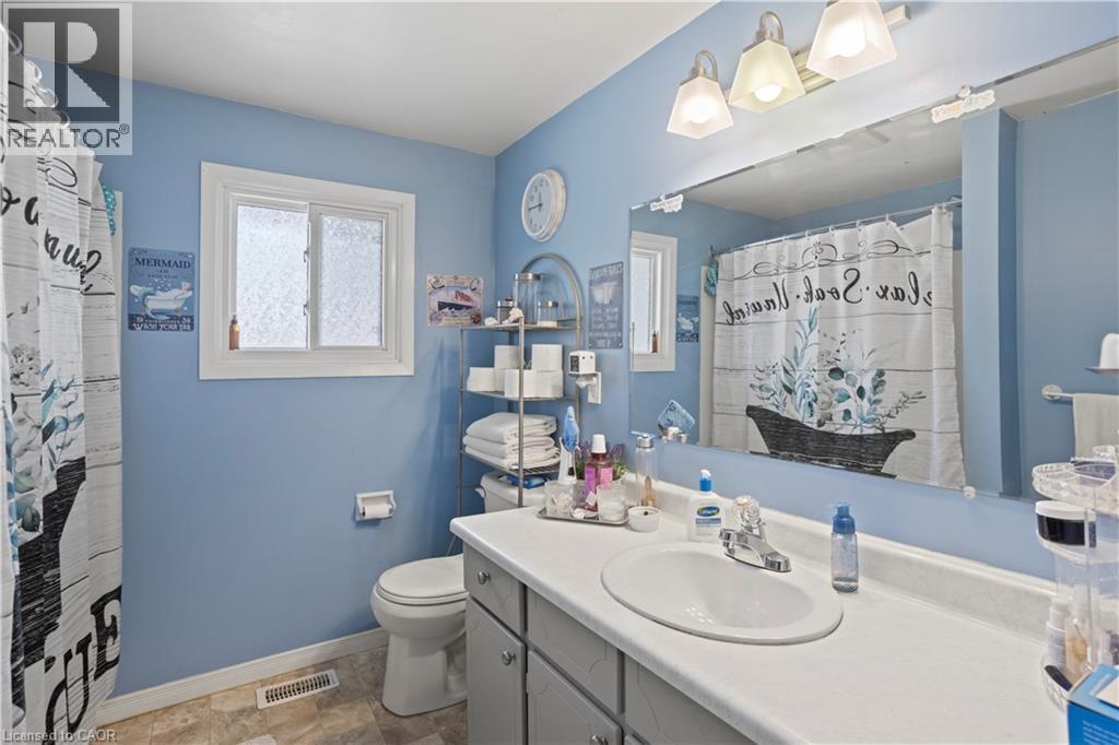 Full bathroom featuring a single vanity, a large wall-mounted mirror, overhead lighting, a toilet, and a window with privacy glass - 179 Vancouver Street, London, ON - Indoor Photo Showing Bathroom
