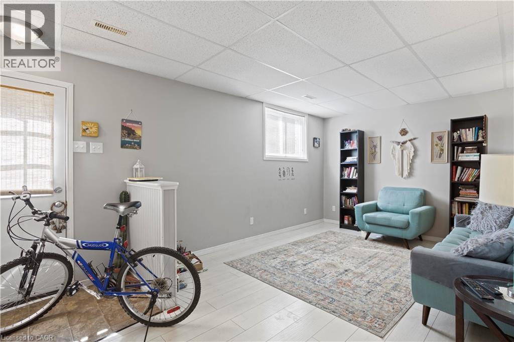 Finished basement space featuring light gray walls, white drop ceiling, and light wood-finish flooring - 179 Vancouver Street, London, ON - Indoor