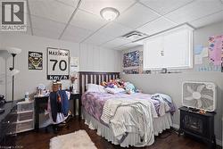 Bedroom featuring wood-finish flooring, light gray walls, and a drop ceiling -