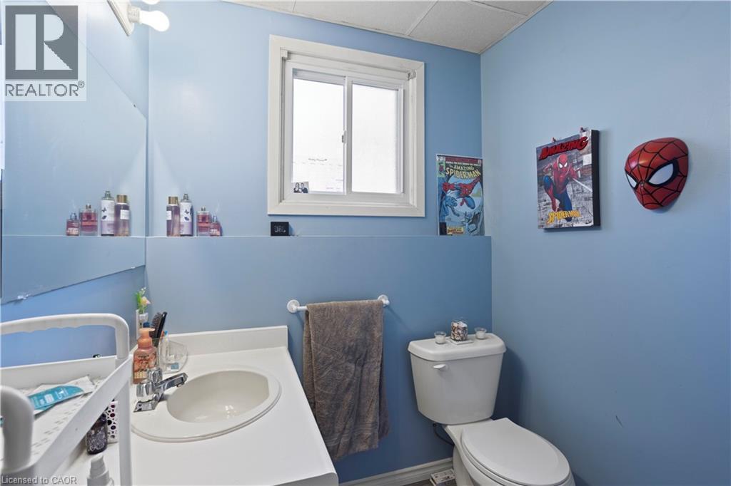 Bathroom featuring a vanity with an integrated sink, a toilet, a window, and a wall-mounted mirror - 179 Vancouver Street, London, ON - Indoor Photo Showing Bathroom
