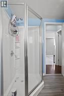 Corner shower enclosure with clear glass panels and chrome-finish framing, featuring a built-in shower caddy and shelving -