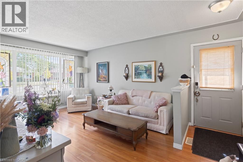 Living space featuring wood-finish flooring, a large picture window with vertical blinds, and light gray wall paint - 179 Vancouver Street, London, ON - Indoor Photo Showing Living Room