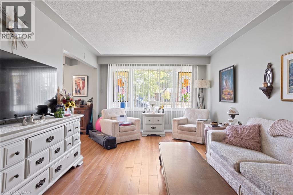 Living area featuring wood-finish flooring, a large window with vertical blinds, and light-toned wall paint - 179 Vancouver Street, London, ON - Indoor Photo Showing Other Room