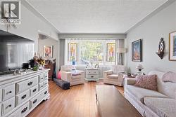 Living area featuring wood-finish flooring, a large window with vertical blinds, and light-toned wall paint -