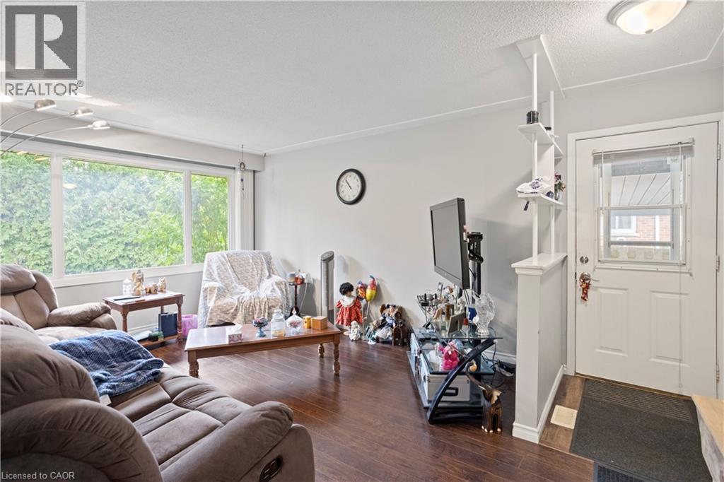 Living area featuring wood-finish flooring, a large window, and a paneled entry door - 179 Vancouver Street, London, ON - Indoor Photo Showing Living Room