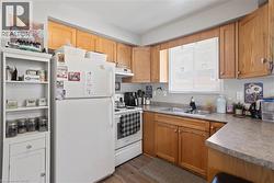 Kitchen featuring wood-finish cabinetry, a double basin stainless steel sink, and light-toned countertops -