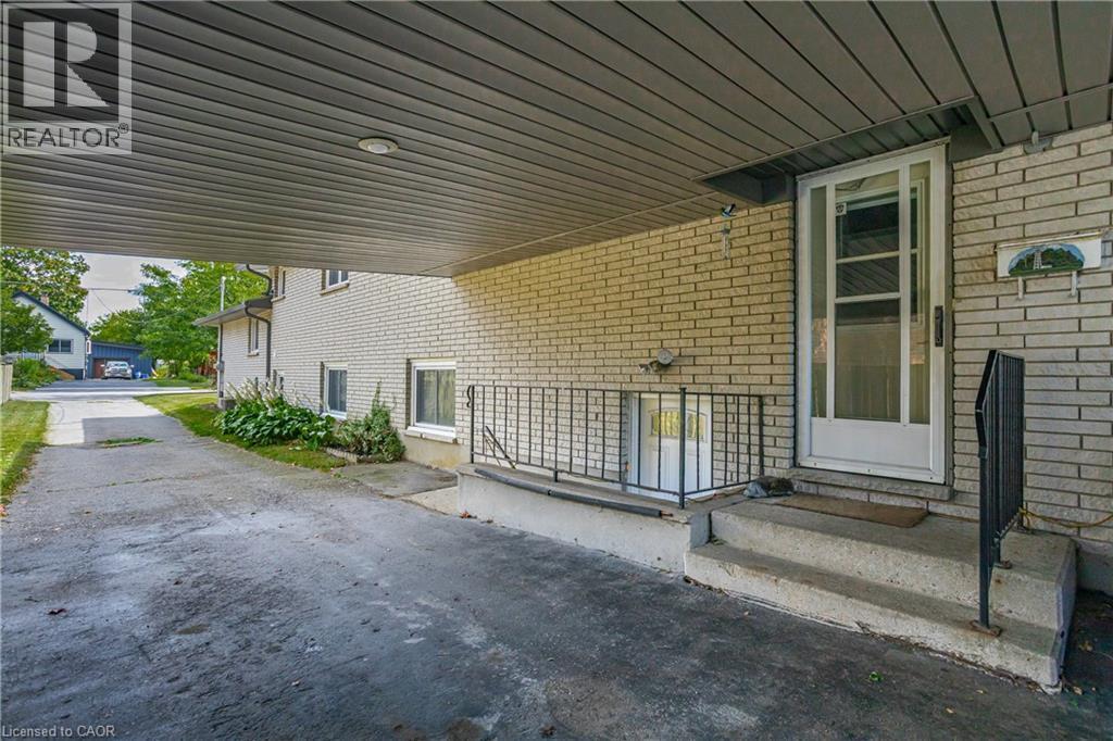 Covered carport parking area with overhead lighting, leading to a brick-clad exterior - 179 Vancouver Street, London, ON - Outdoor With Exterior
