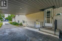 Covered carport parking area with overhead lighting, leading to a brick-clad exterior -