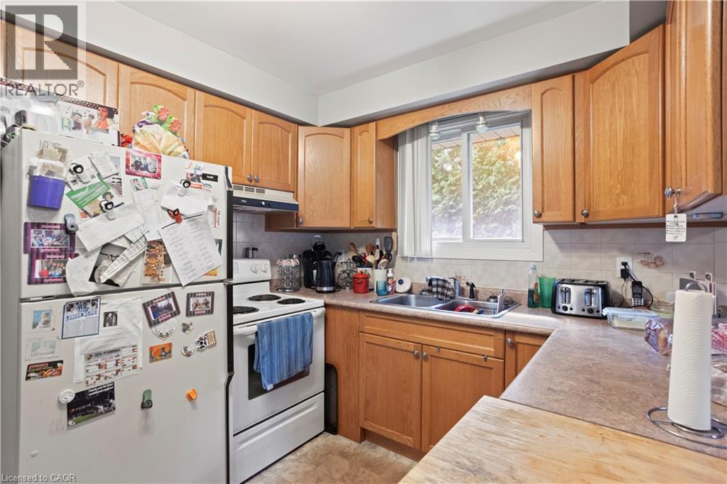 Kitchen featuring wood-finish cabinetry, a double-basin stainless steel sink, and a window above the sink - 179 Vancouver Street, London, ON - Indoor Photo Showing Kitchen With Double Sink