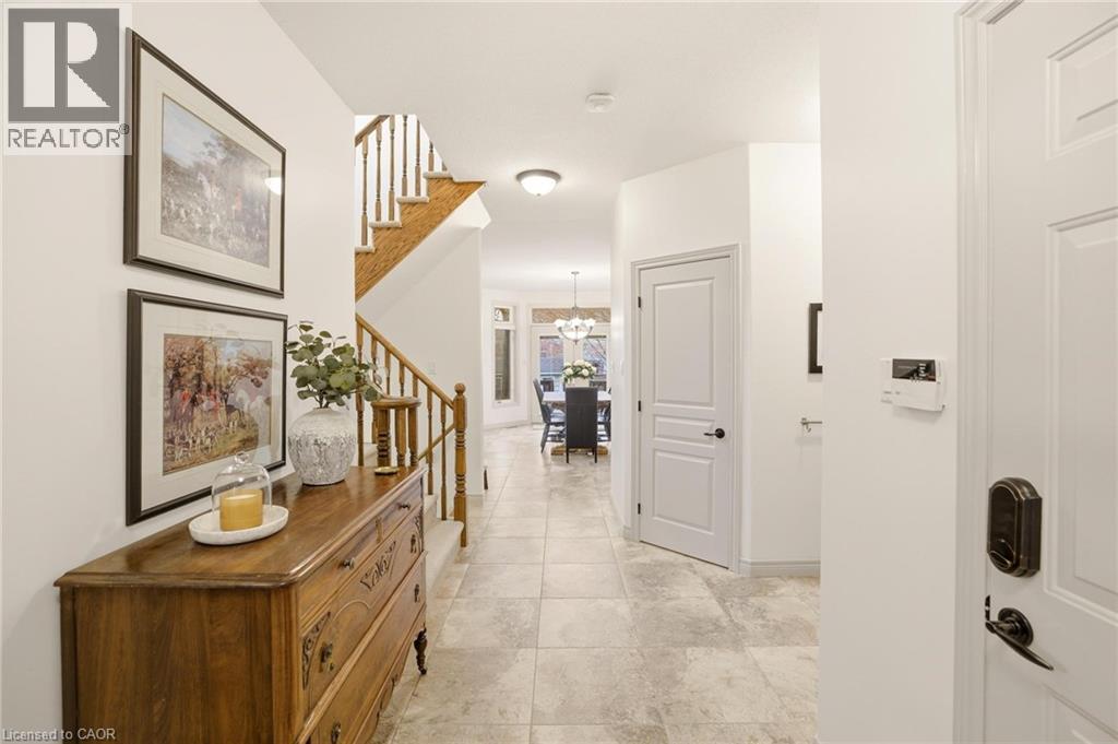 Bright entryway featuring tile flooring and a staircase with wood newel posts and handrail - 129 Magnificent Way, Binbrook, ON - Indoor Photo Showing Other Room