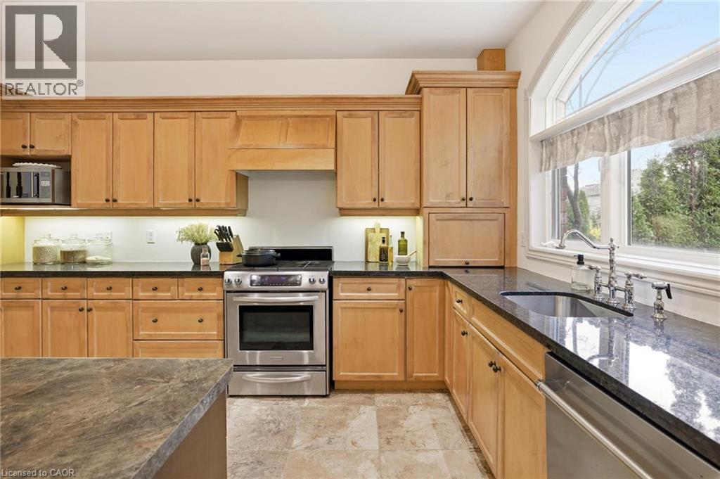 Kitchen featuring light wood cabinetry with dark hardware, dark countertops, a stainless steel range, and an undermount sink with a gooseneck faucet - 129 Magnificent Way, Binbrook, ON - Indoor Photo Showing Kitchen