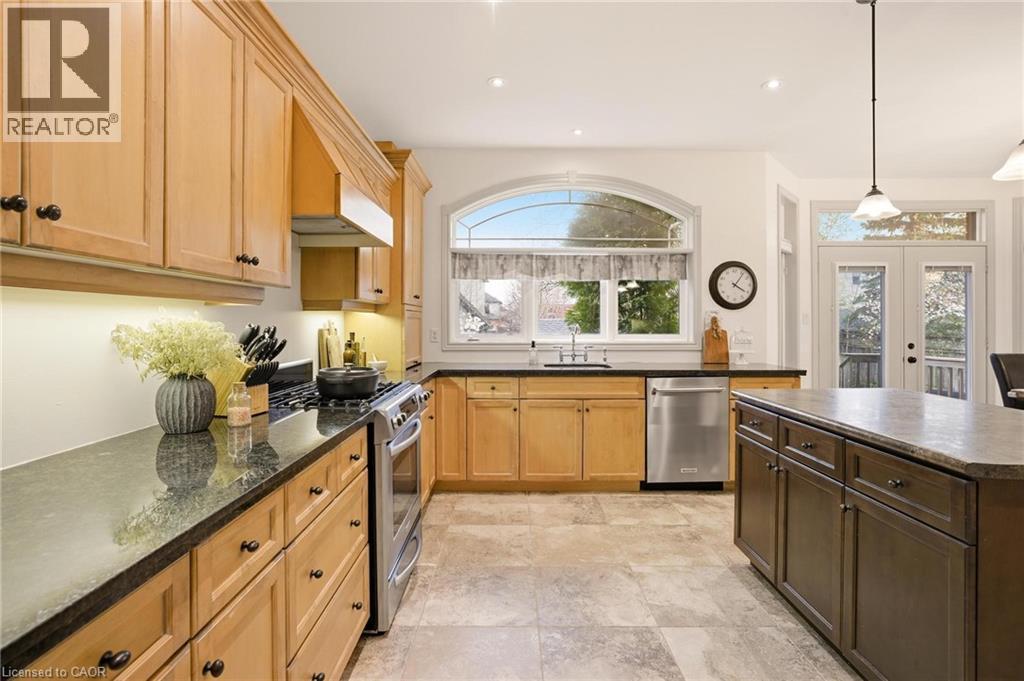 Contemporary kitchen featuring light wood cabinetry, dark countertops, and stainless steel appliances - 129 Magnificent Way, Binbrook, ON - Indoor Photo Showing Kitchen