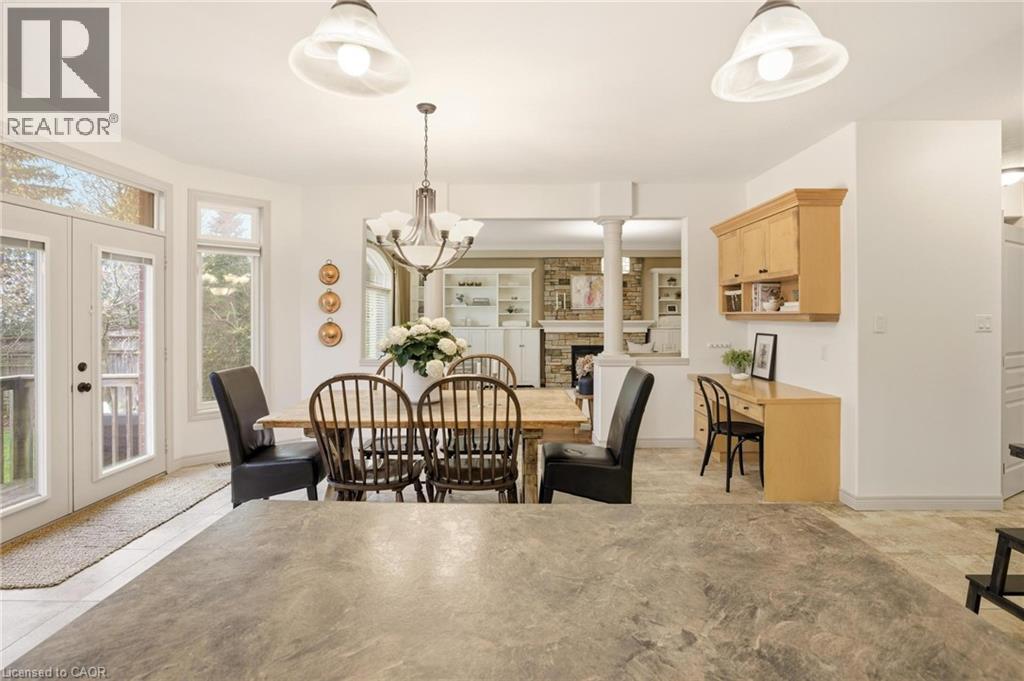 Dining area featuring a chandelier, French doors leading to an exterior deck, and an integrated desk with upper cabinetry - 129 Magnificent Way, Binbrook, ON - Indoor Photo Showing Dining Room