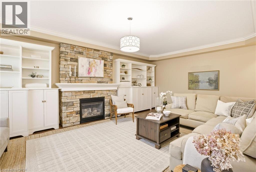 Stone-clad fireplace with mantel and gas insert, flanked by built-in white cabinetry with open shelving - 129 Magnificent Way, Binbrook, ON - Indoor Photo Showing Living Room With Fireplace