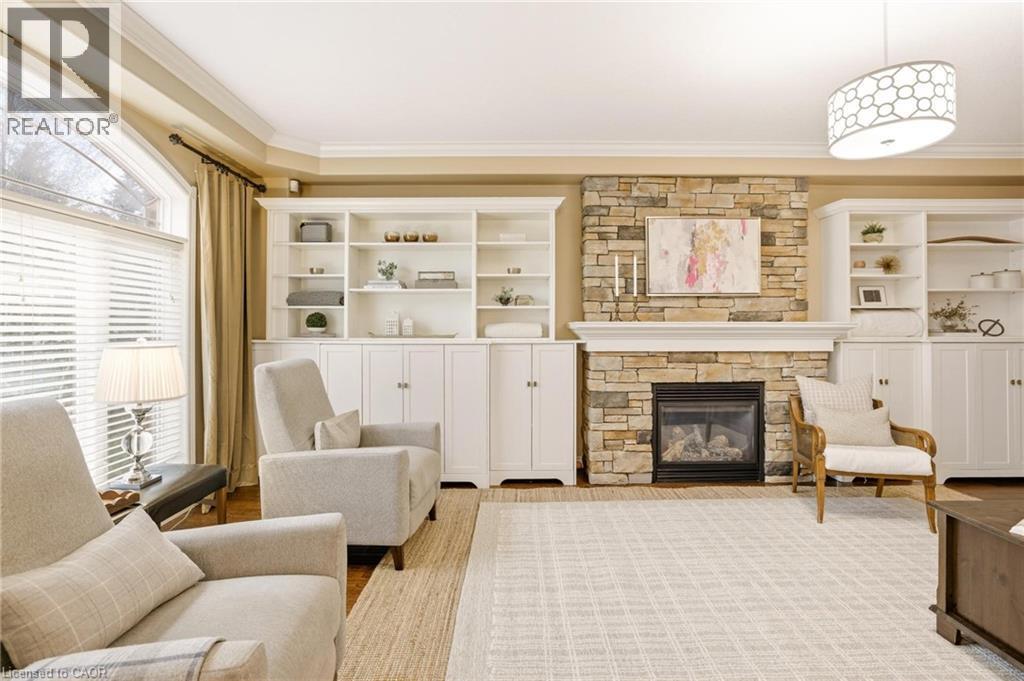 Stacked stone fireplace with a white mantel, flanked by built-in white cabinetry and shelving - 129 Magnificent Way, Binbrook, ON - Indoor Photo Showing Living Room With Fireplace