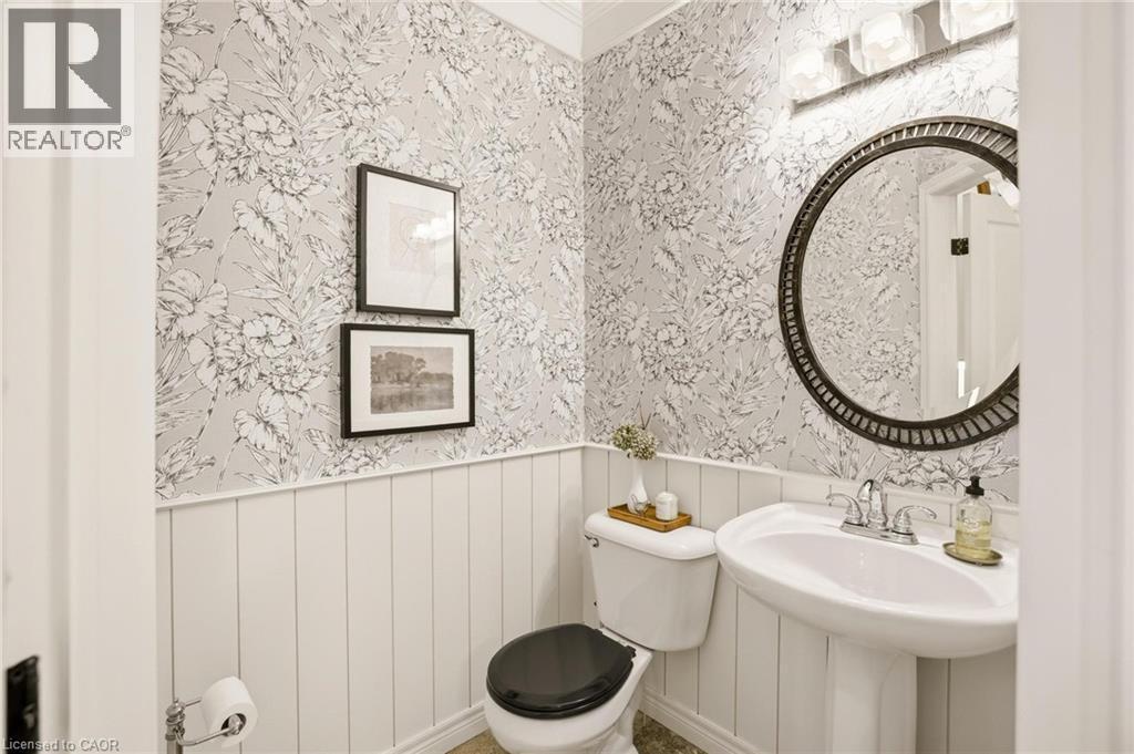 Pedestal sink with chrome faucet, complemented by a round framed mirror above - 129 Magnificent Way, Binbrook, ON - Indoor Photo Showing Bathroom