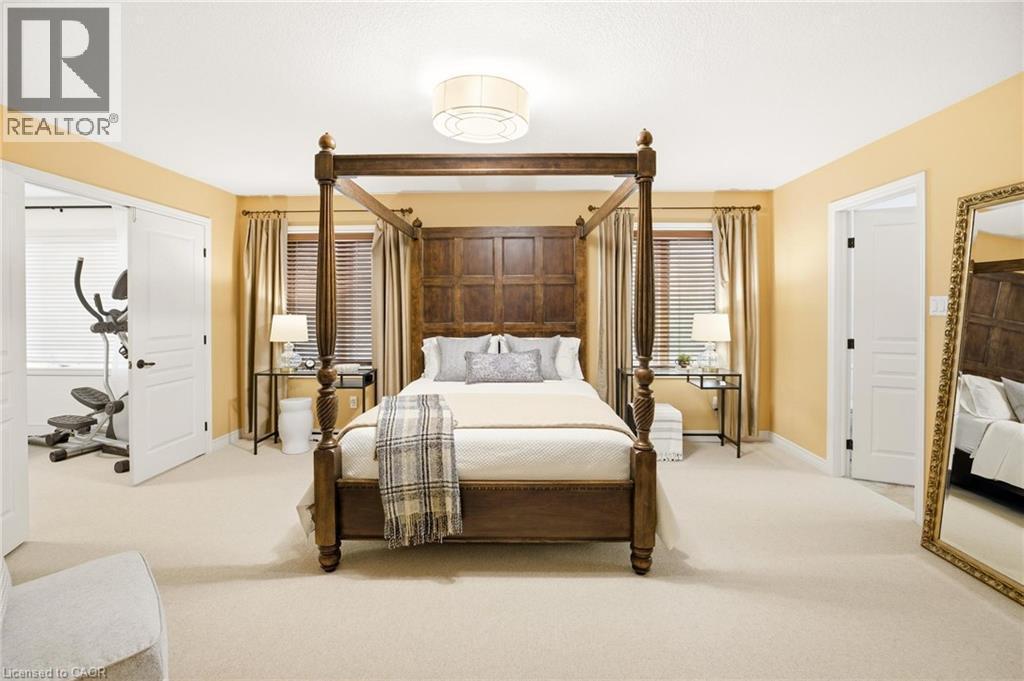 Spacious room featuring light-colored carpeting, two paneled windows with blinds, and a double-door entryway to an additional room - 129 Magnificent Way, Binbrook, ON - Indoor Photo Showing Bedroom