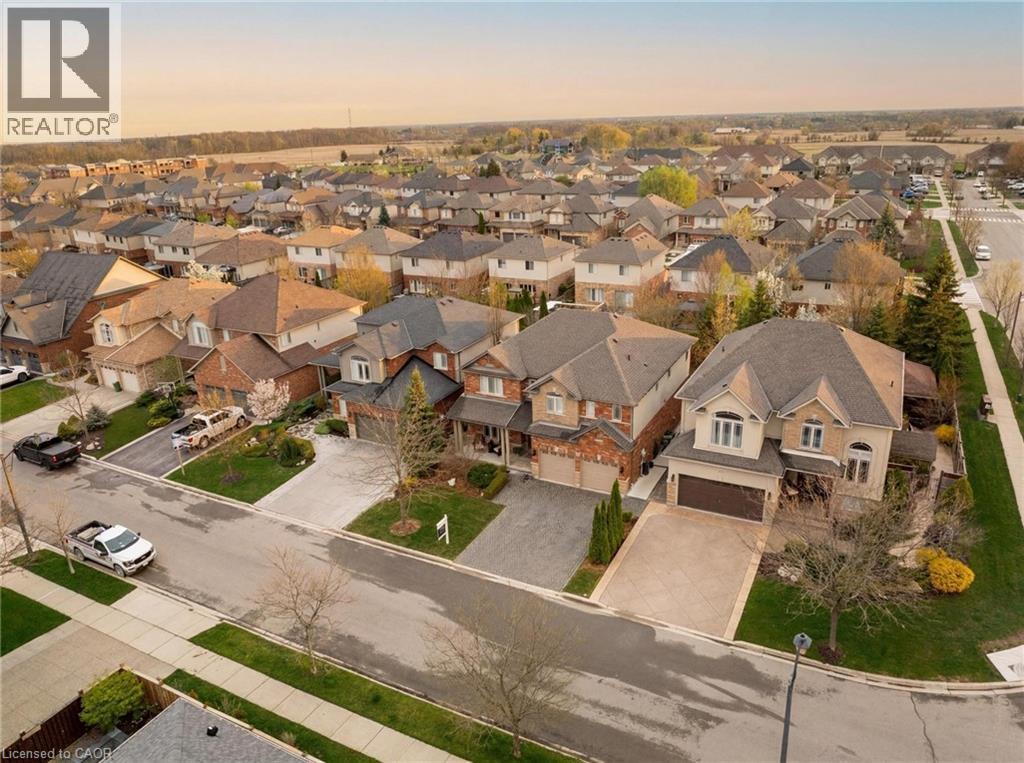 Residential street featuring two-story homes with brick and stucco exteriors, attached garages, and paved driveways - 129 Magnificent Way, Binbrook, ON - Outdoor With View