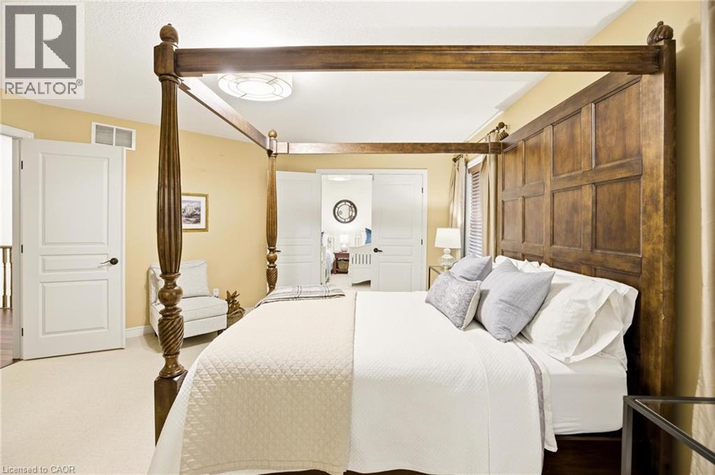 Carpeted bedroom featuring a circular ceiling light fixture, white interior doors with dark hardware, and a window with blinds and drapes - 129 Magnificent Way, Binbrook, ON - Indoor Photo Showing Bedroom
