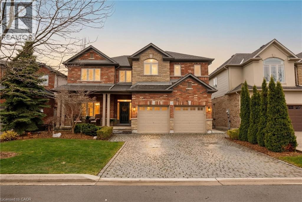 Brick and stone facade residence featuring a covered front porch, a two-car garage, and a paver driveway - 129 Magnificent Way, Binbrook, ON - Outdoor With Facade
