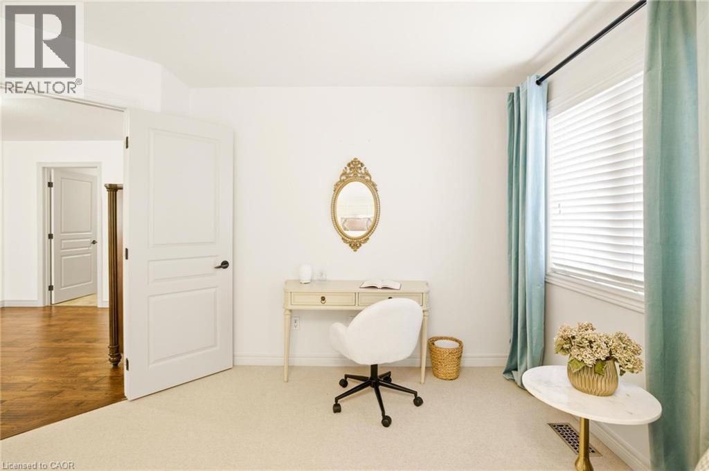 Room featuring neutral carpeting, a large window with white blinds and light-colored drapes, and a white paneled door with black hardware - 129 Magnificent Way, Binbrook, ON - Indoor