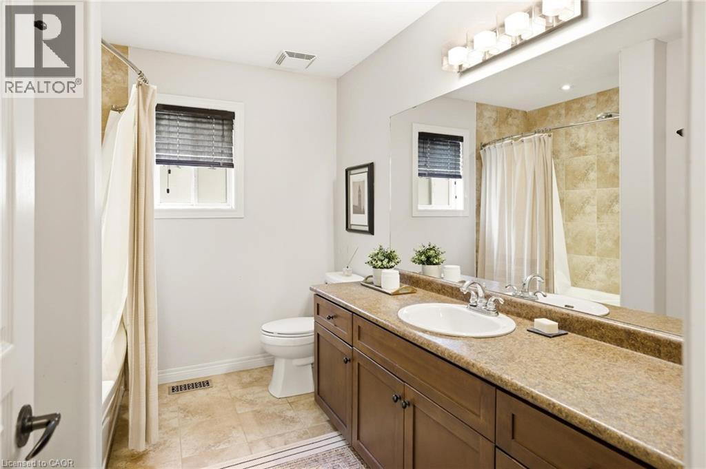 Bathroom with a brown wood-finish vanity, integrated sink, and an expansive mirror - 129 Magnificent Way, Binbrook, ON - Indoor Photo Showing Bathroom